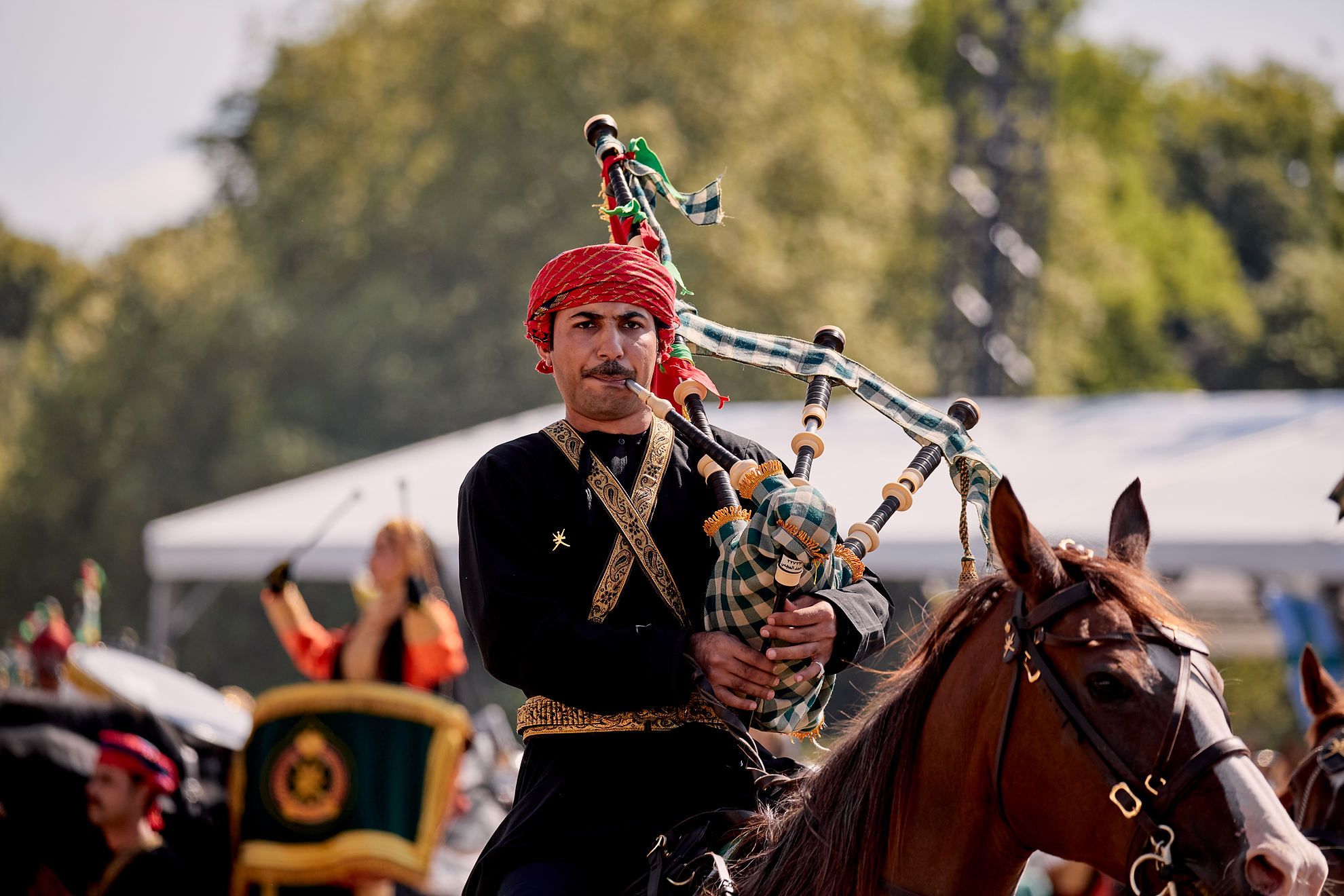 Ein Mann von "the Combined Bands of the Royal Cavalry and the Royal Guard of Oman" Dudelsack spielend auf einem Pferd.